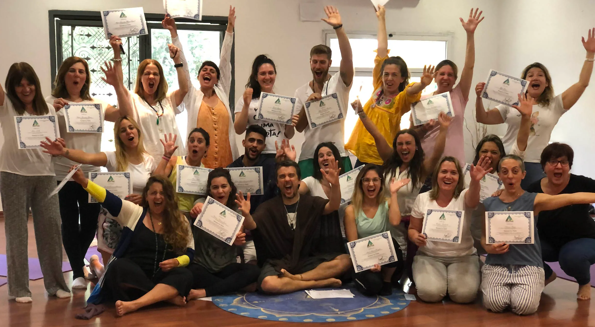 Grupo numeroso de alumnos celebrando con certificados de Reikitime tras una iniciación