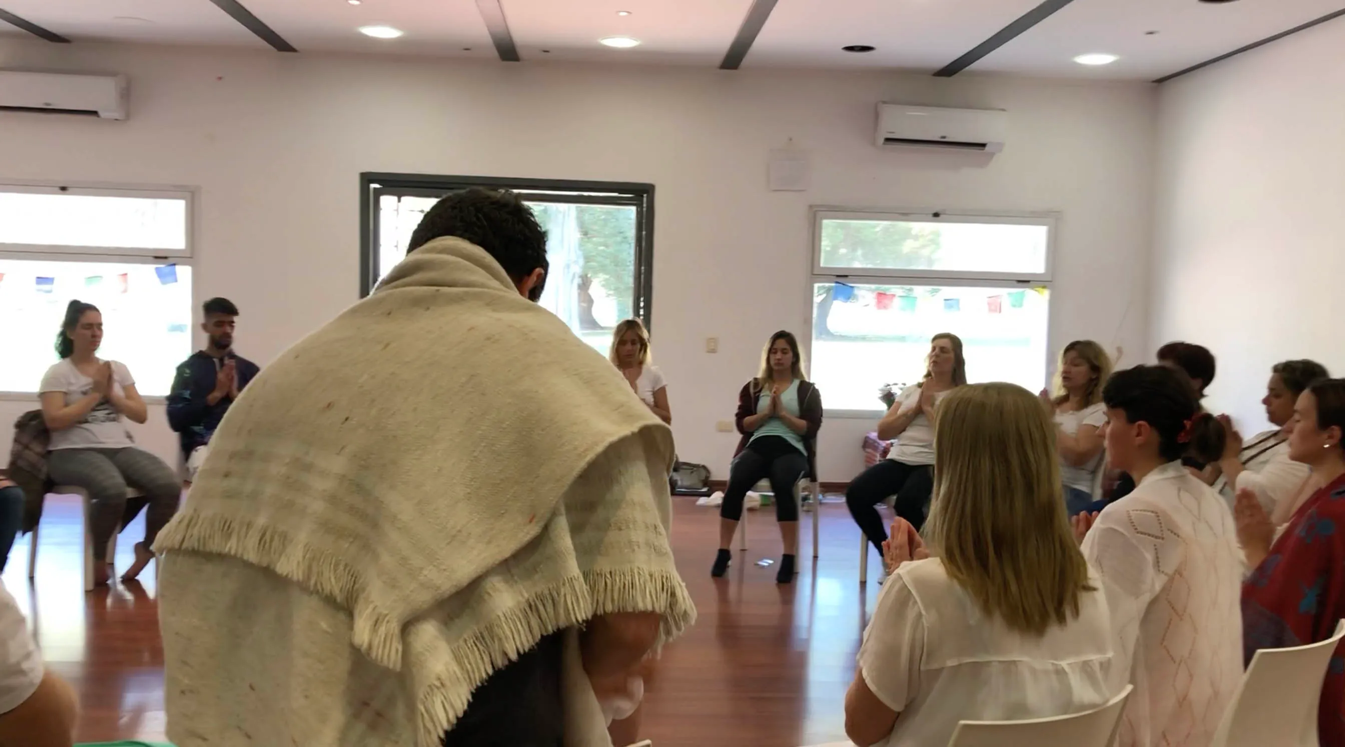 Matías Mahia dando una sintonización de Reiki a un grupo, cubierto con manta tradicional durante el ritual de Reiju