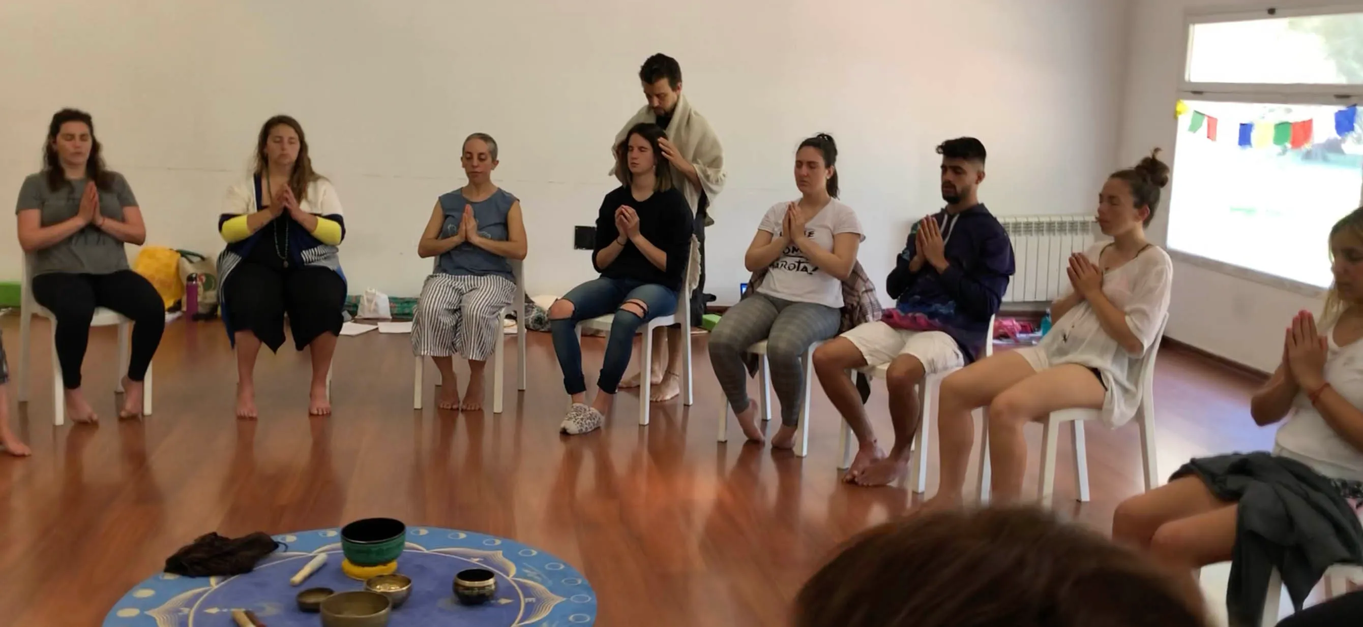 Grupo de practicantes recibiendo Reiki sentados en círculo, sostenidos por sus pares en una iniciación con Matías Mahia